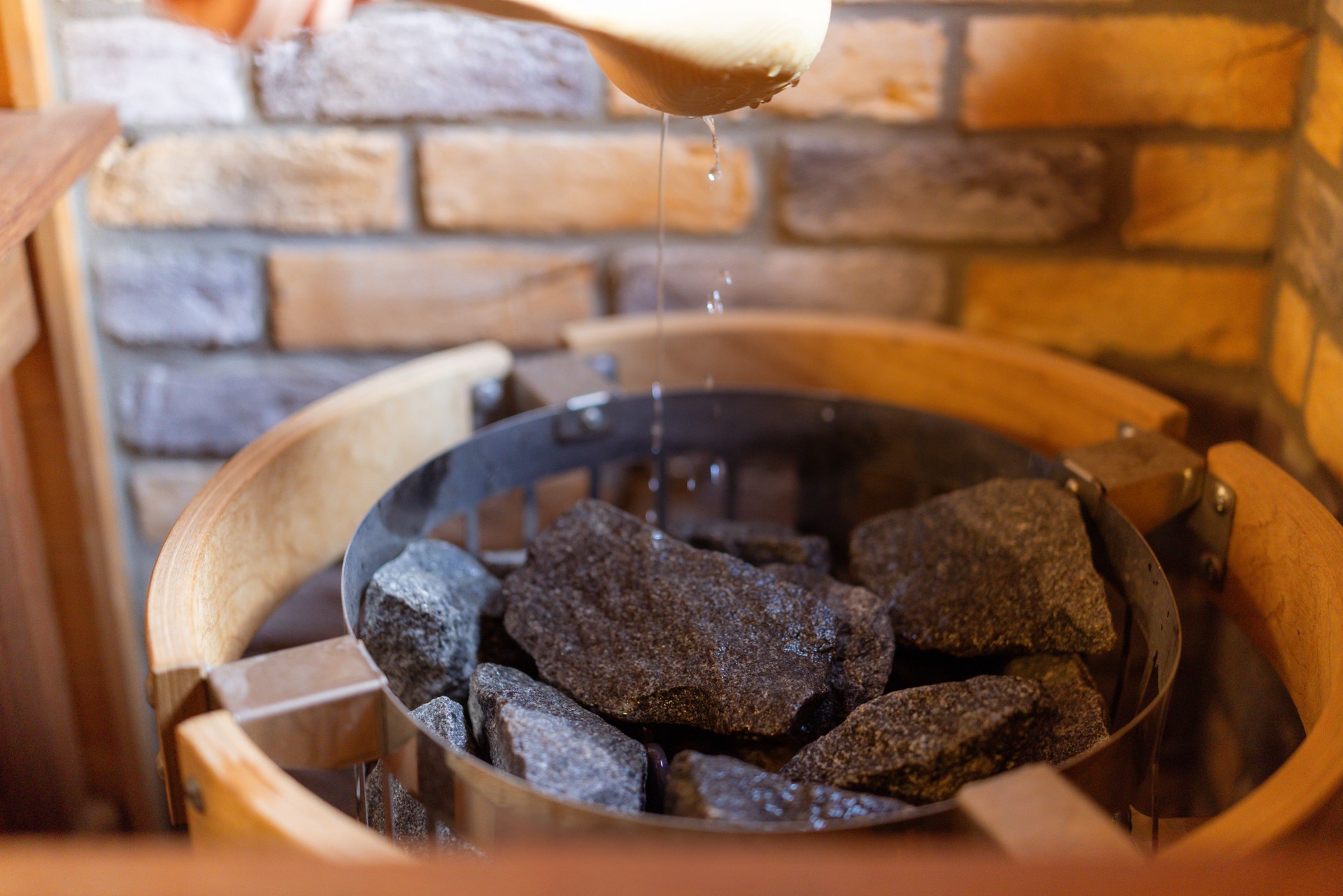 Young woman pouring water on sauna stones